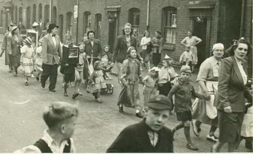 Winson Street Coronation Celebration in 1953, the Children’s Procession walked through the local streets,  this was taken as we walked along Cape Street, I am the little girl dressed as Red Riding Hood carrying the basket, holding my Mum’s hand, my Mum had made my costume ( I was two & a half at the time ).  The party for the part of Winson Street we lived in centred on the Bellfield Pub, all the children were given commemorative bibles.
